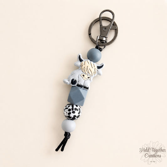 Keychain with cow design on a beige background