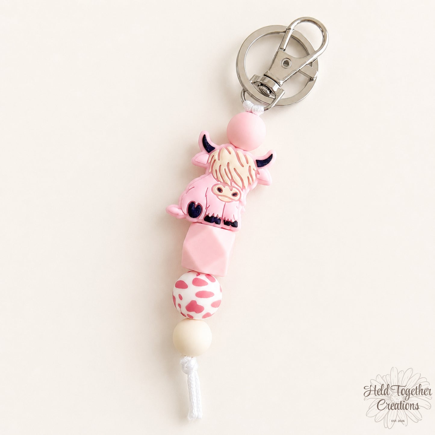 Pink cow-shaped keychain with a white background
