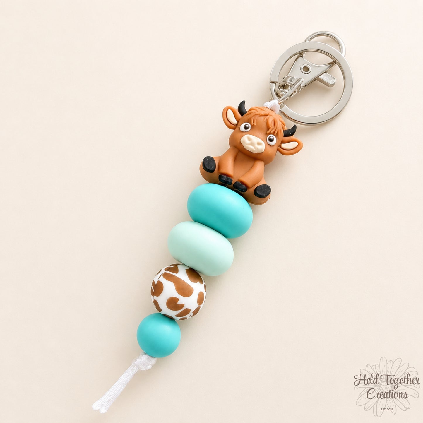 Keychain with cow charm and turquoise beads on a beige background