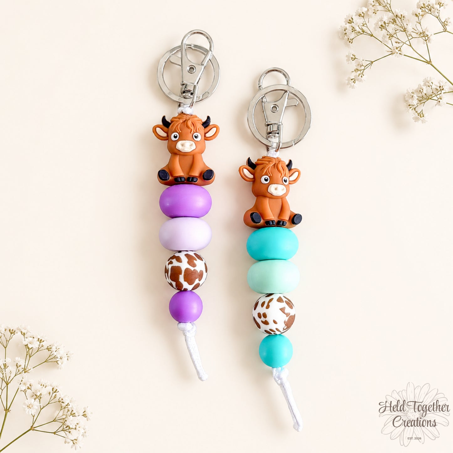 Two keychains with cow charms and colorful beads on a light background.