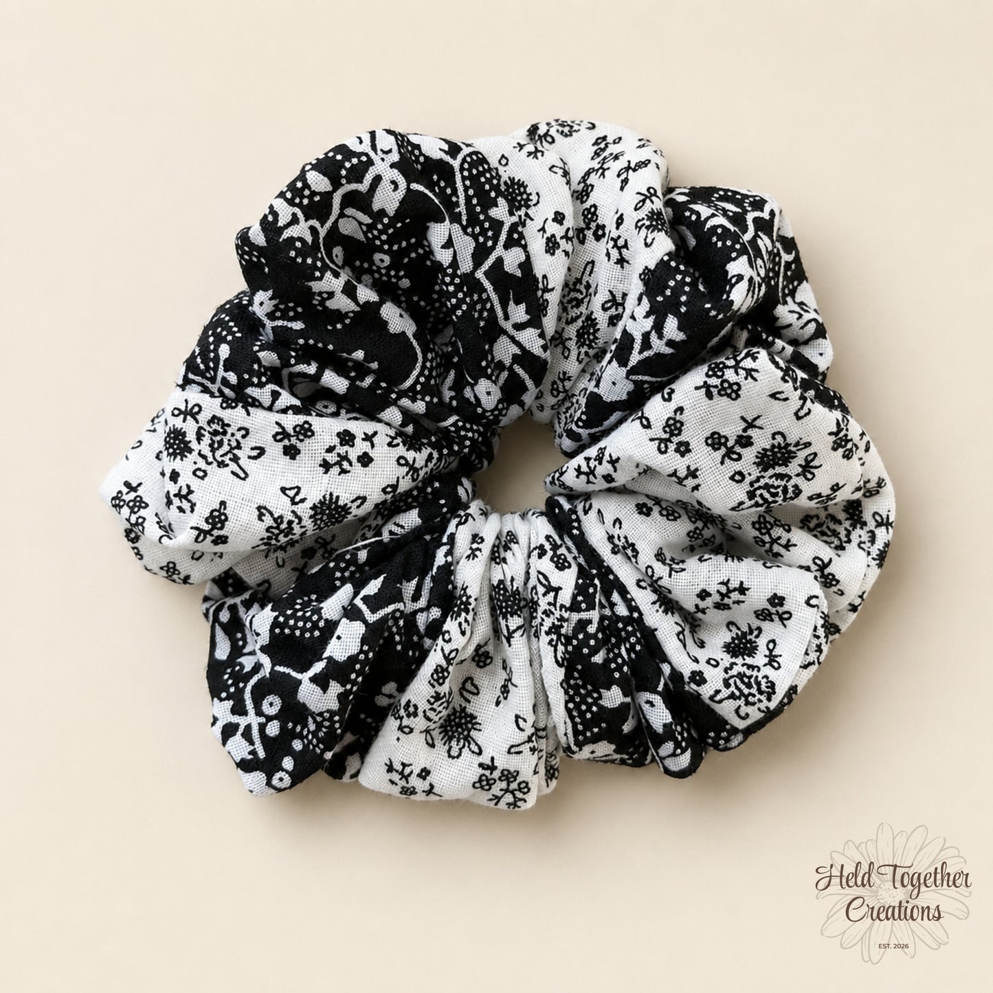 Ink Bloom Scrunchie with black and white floral print on a warm ivory background.
