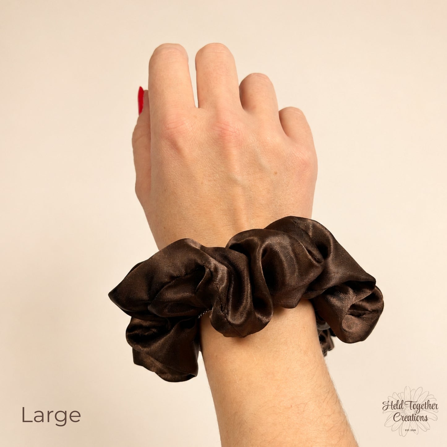 Large brown satin scrunchie worn on wrist showing rich brown glossy fabric and oversized gathered style.