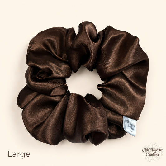 Large brown satin scrunchie on a warm ivory background with glossy gathered fabric and HTC label.