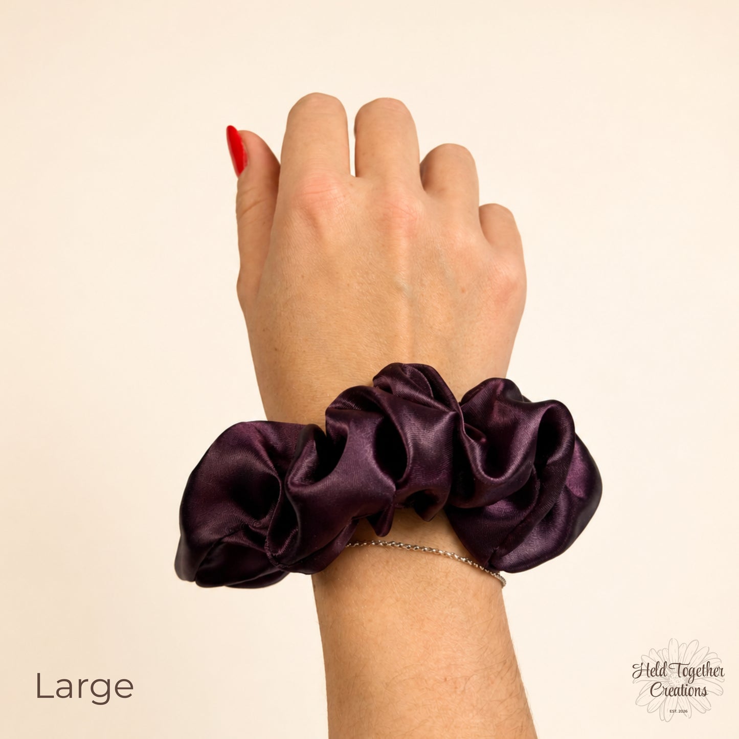 Large deep plum satin scrunchie worn on wrist showing glossy satin texture