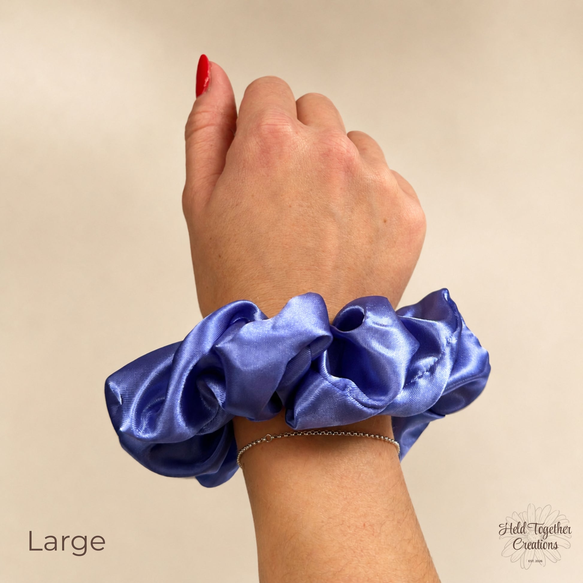 Large lilac satin scrunchie worn on wrist against a warm ivory background.