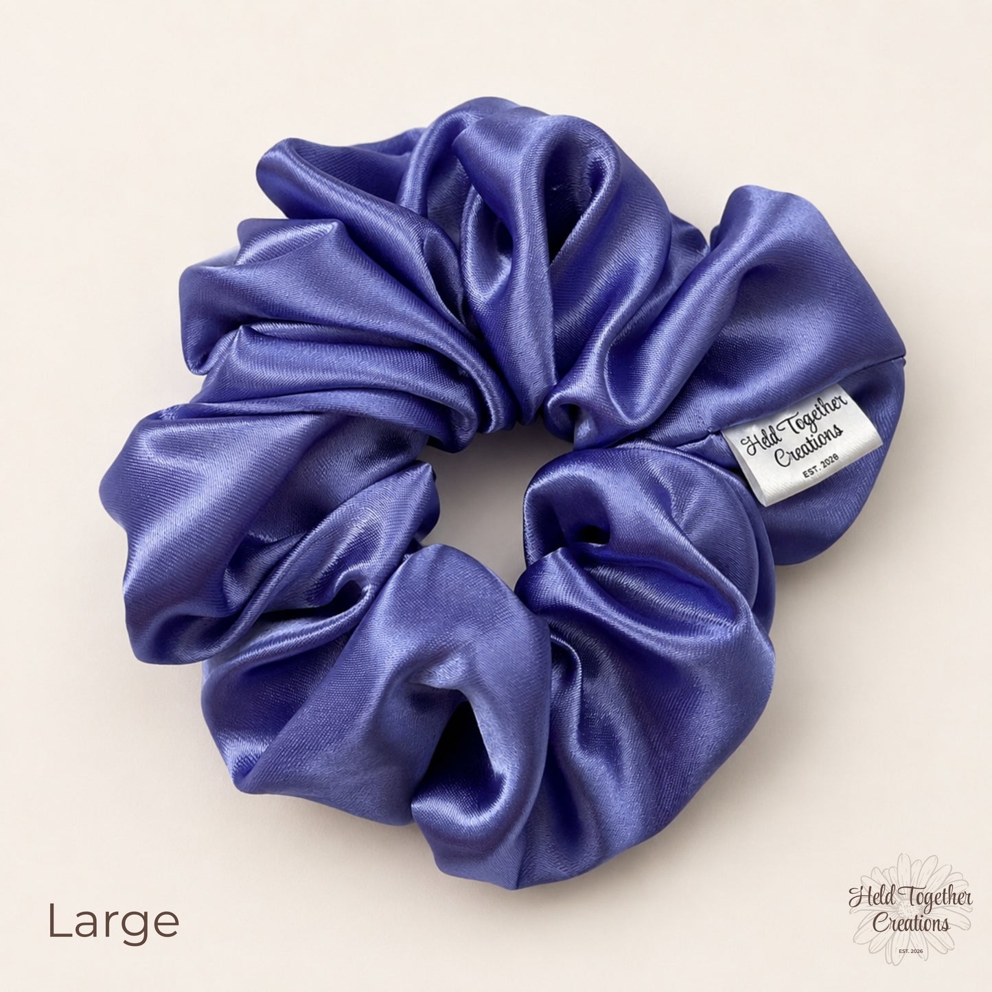 Large lilac satin scrunchie laid flat showing glossy gathered fabric and brand tag.
