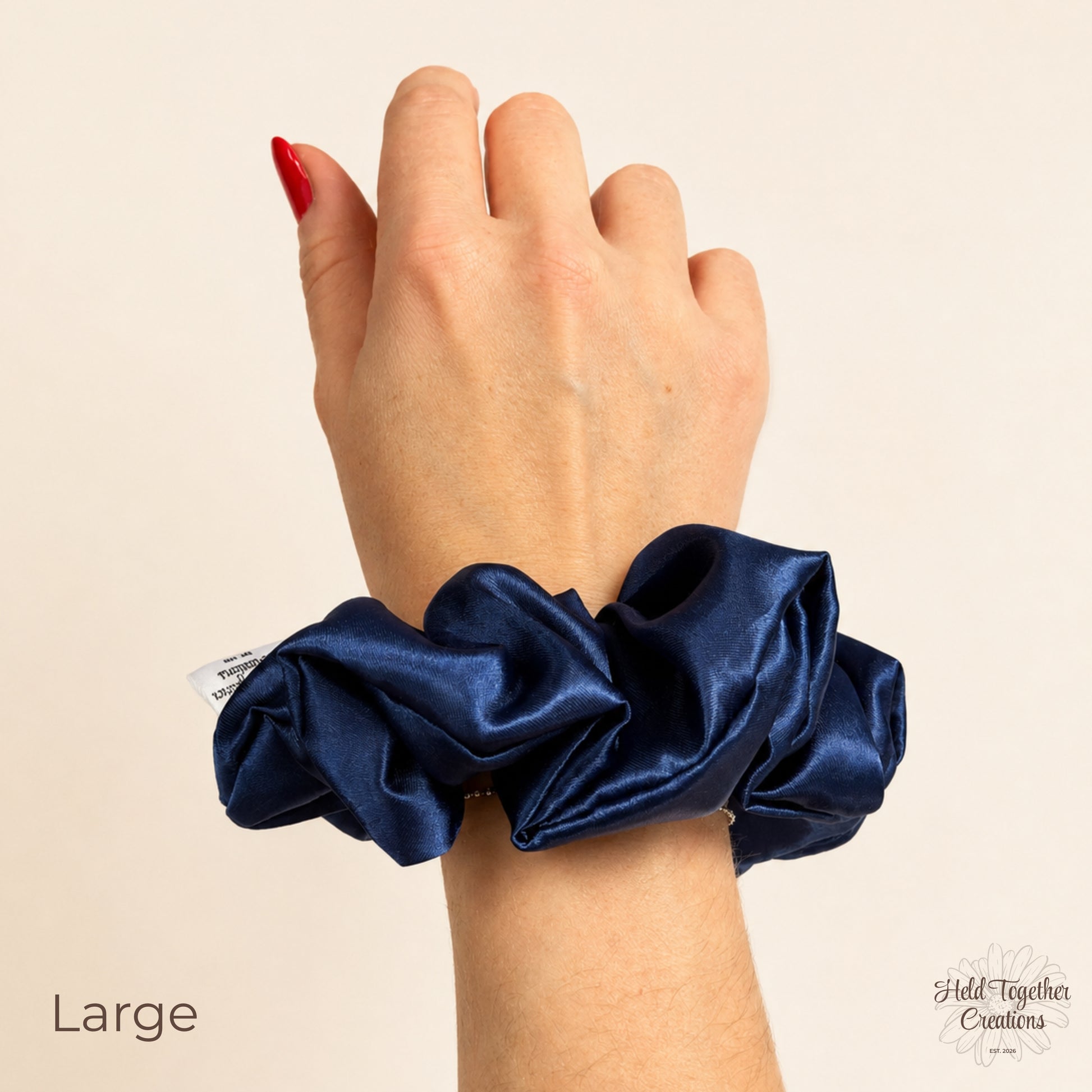 Large navy satin scrunchie worn on wrist to show size and shiny satin texture.