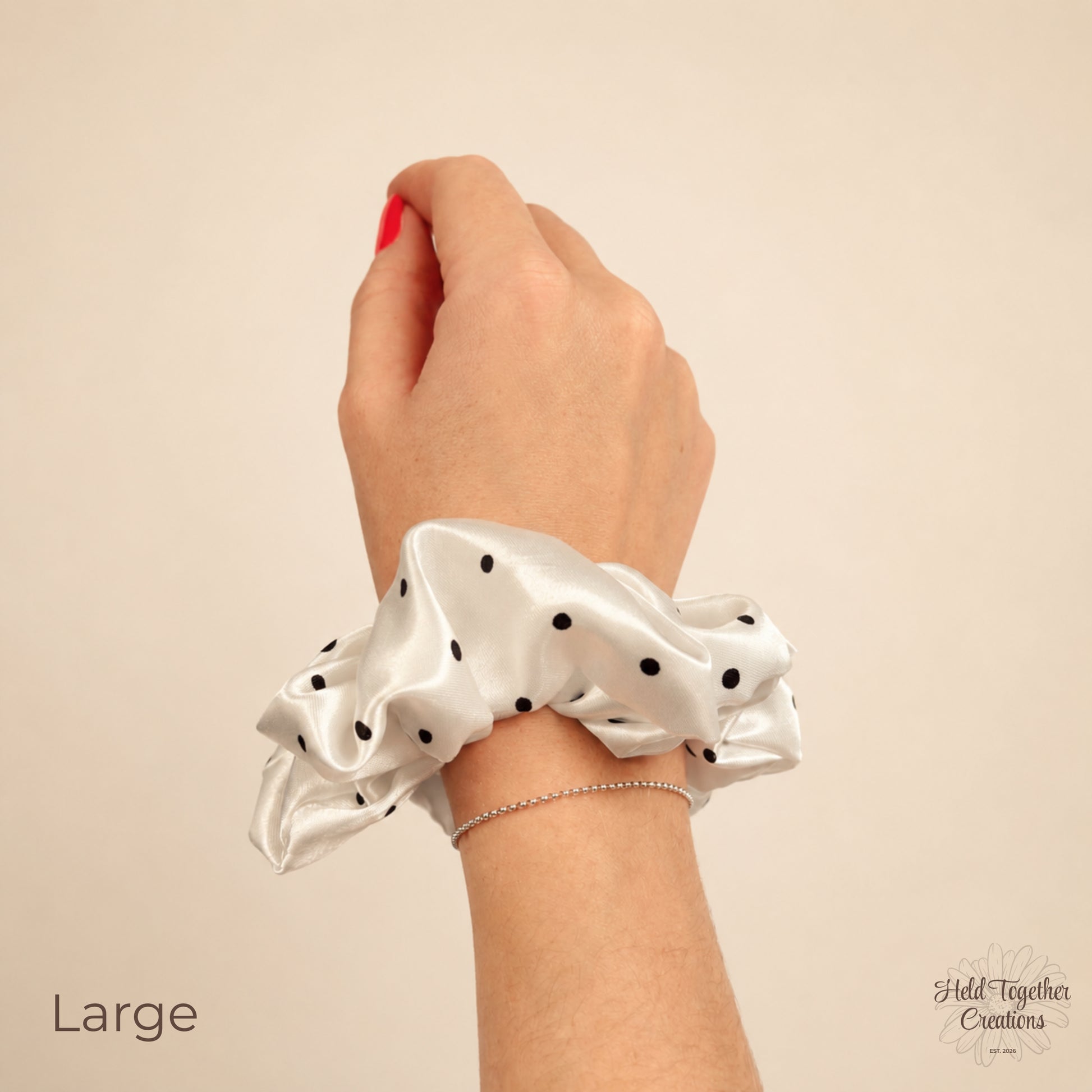 Large white satin scrunchie with black polka dots worn on wrist.