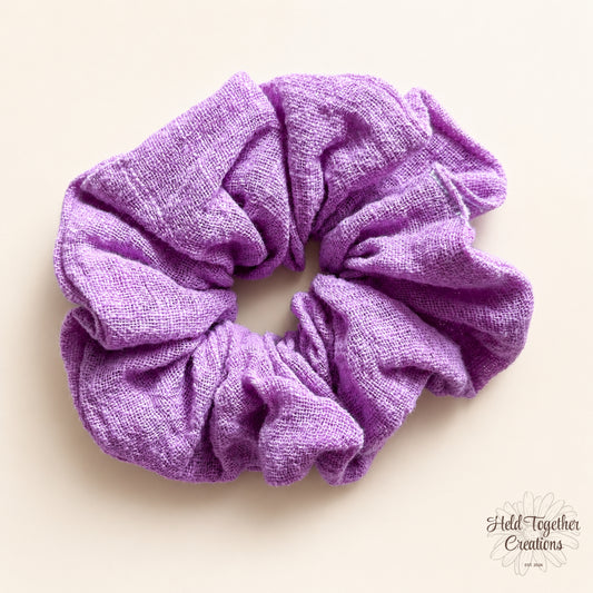 Lilac textured linen-look fabric scrunchie on a warm ivory background.