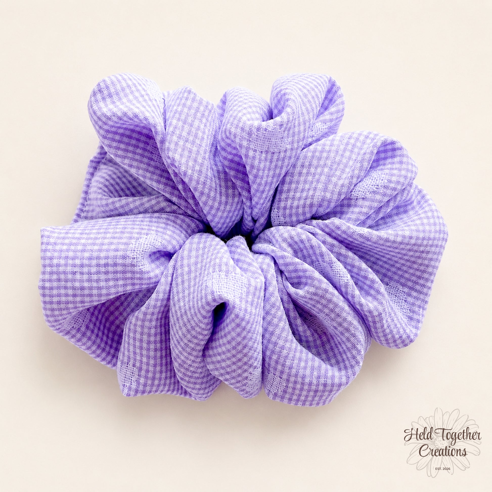 Lilac and white check handmade fabric scrunchie on a soft ivory background.