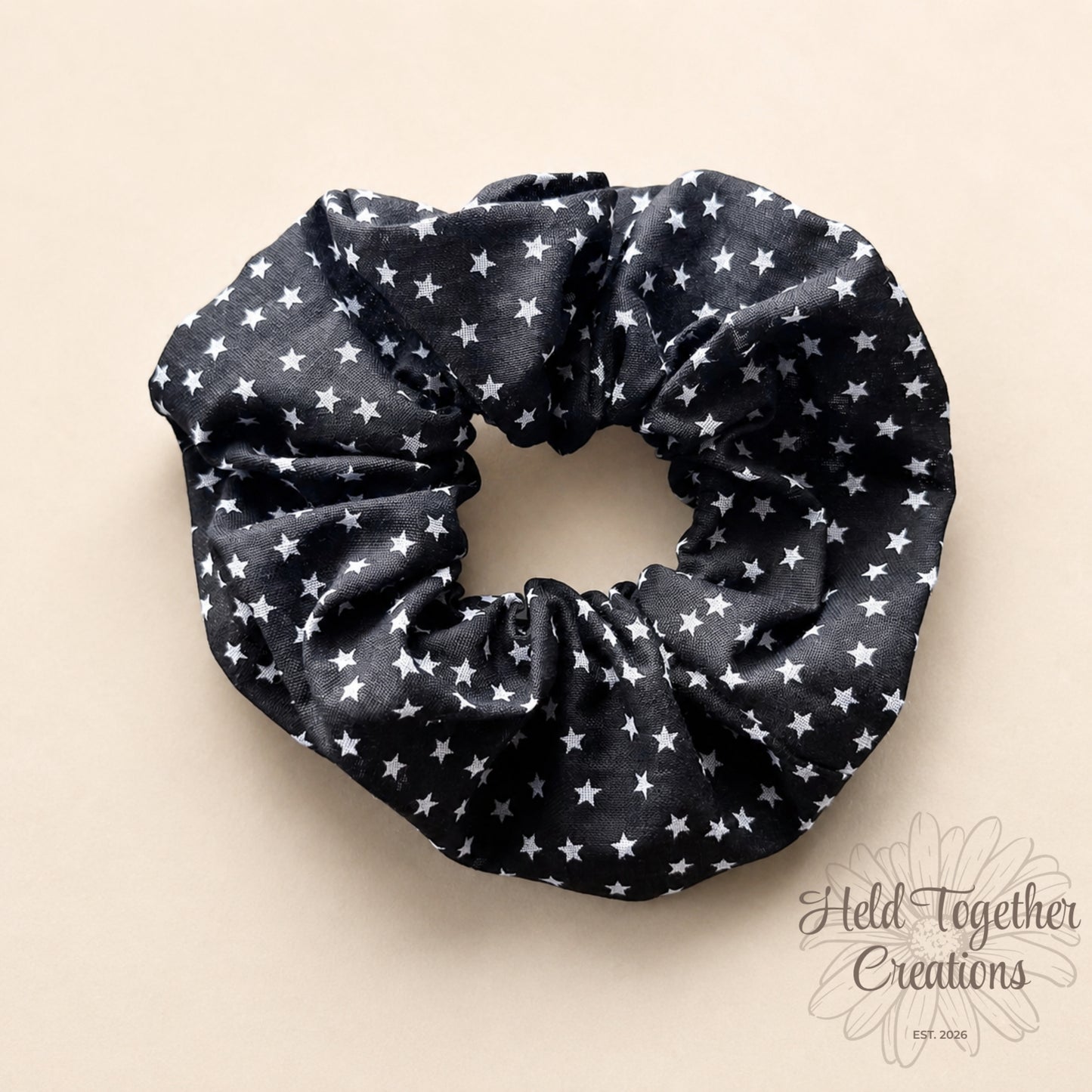 Black scrunchie with white star pattern on a beige background
