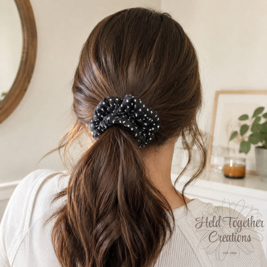 Person with a ponytail held together with a polka dot scrunchie, indoor setting.