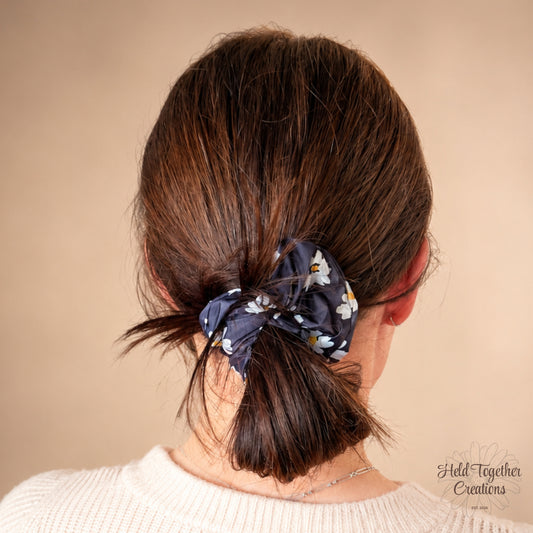 Moonlit Daisy Scrunchie with black fabric and white daisy floral print, handmade by Held Together Creations.