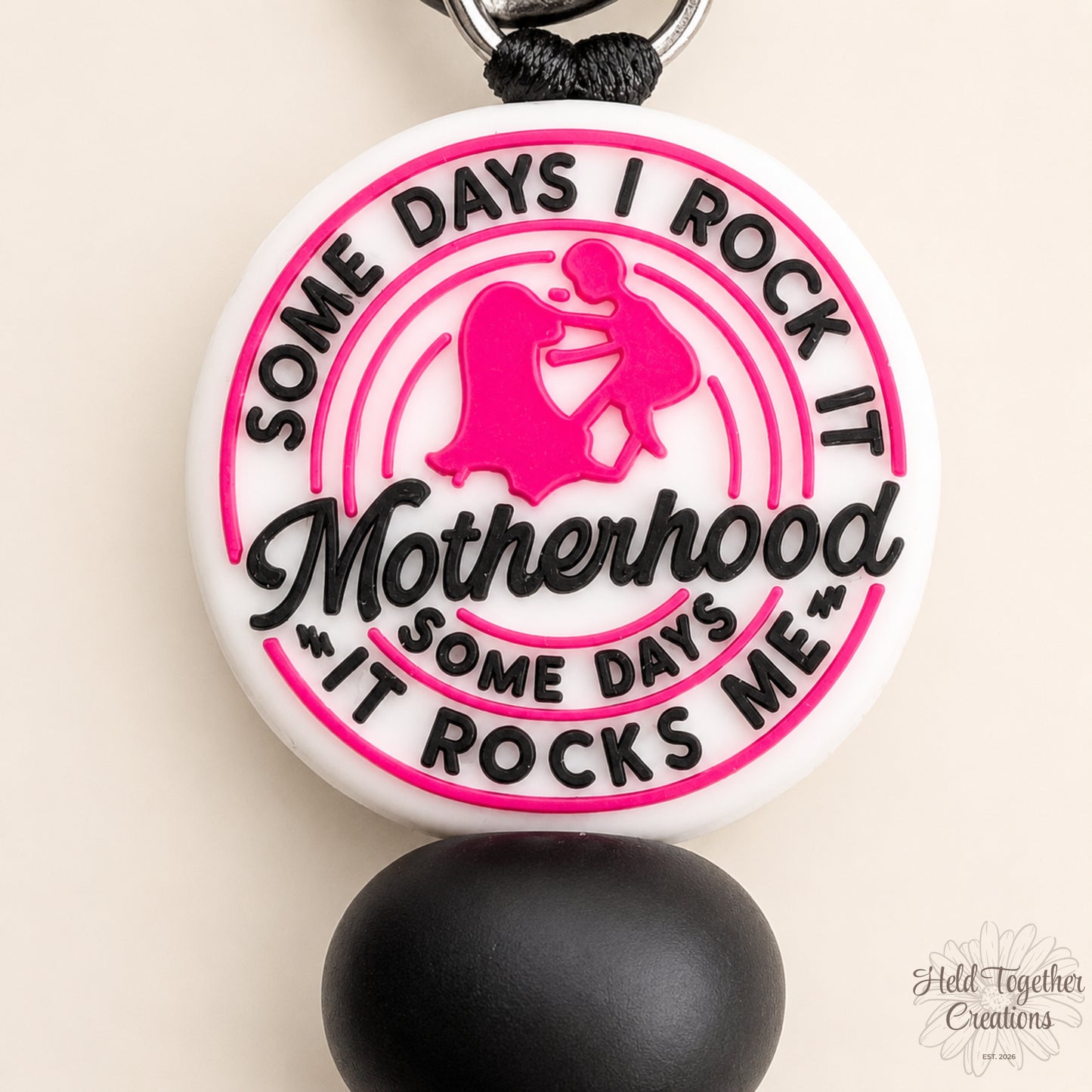 Handmade Motherhood Rocks silicone bead keyring with pink, black and white beads on a warm ivory background.