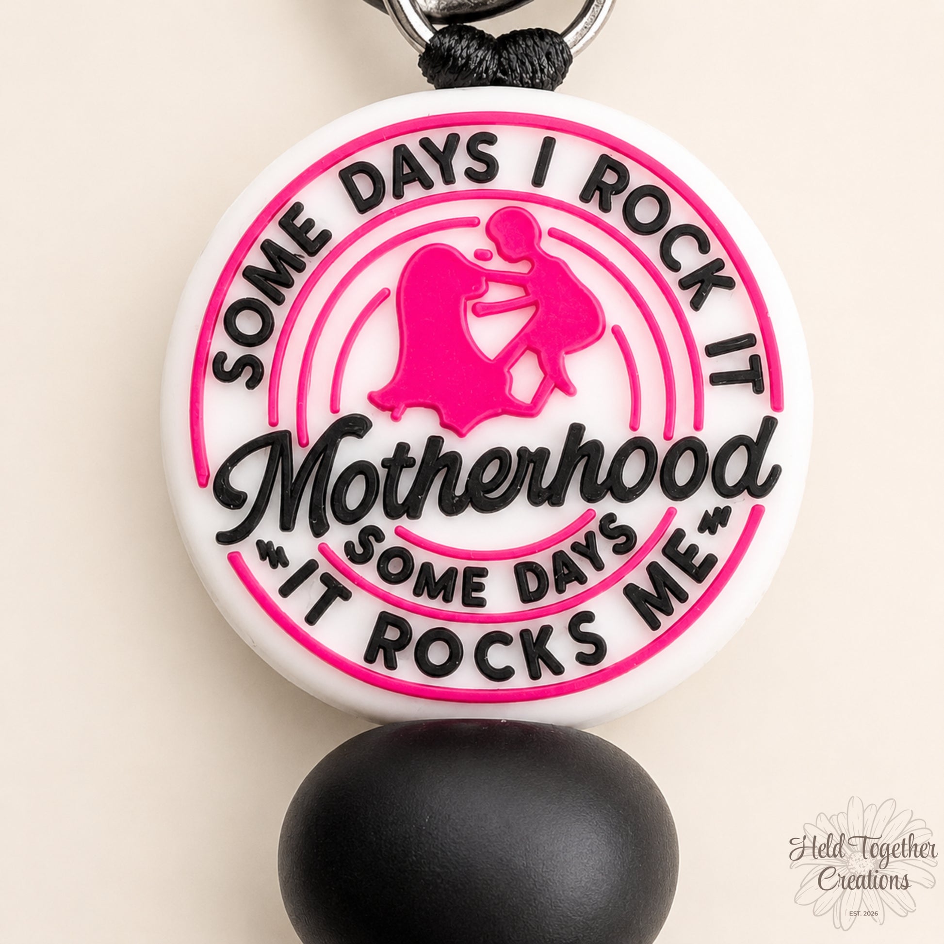 Handmade Motherhood Rocks silicone bead keyring with pink, black and white beads on a warm ivory background.