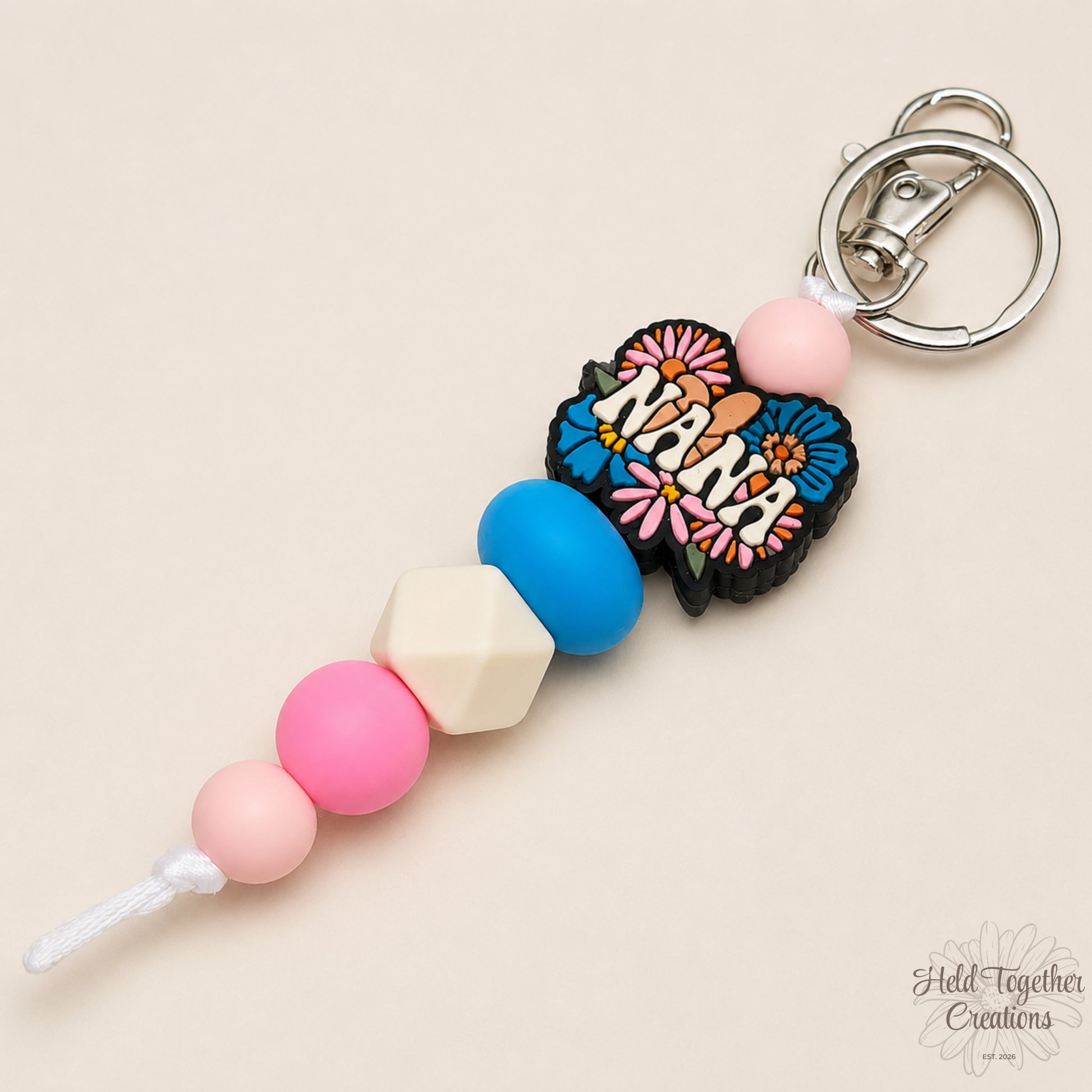 Handmade Nana silicone bead keyring with pink, blue and cream beads, floral Nana charm and silver keyring hardware.