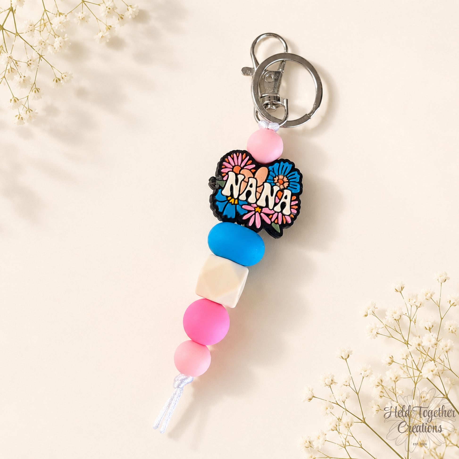 Handmade Nana silicone bead keyring with pink, blue and cream beads, floral Nana charm and silver keyring hardware.