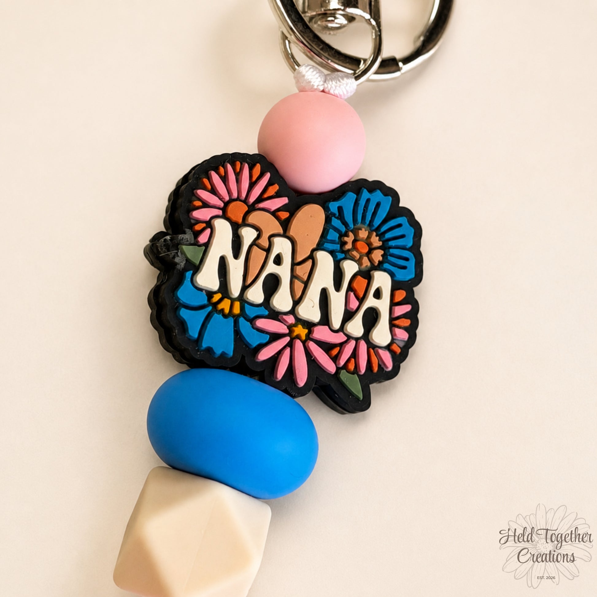 Handmade Nana silicone bead keyring with pink, blue and cream beads, floral Nana charm and silver keyring hardware.