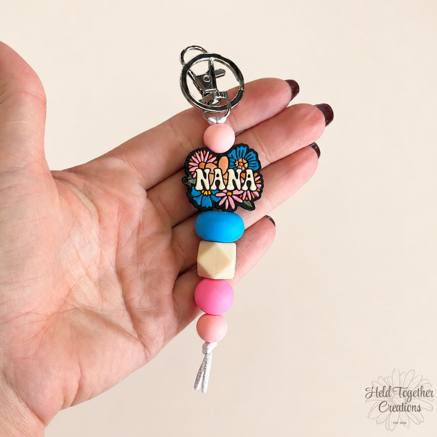 Handmade Nana silicone bead keyring with pink, blue and cream beads, floral Nana charm and silver keyring hardware.