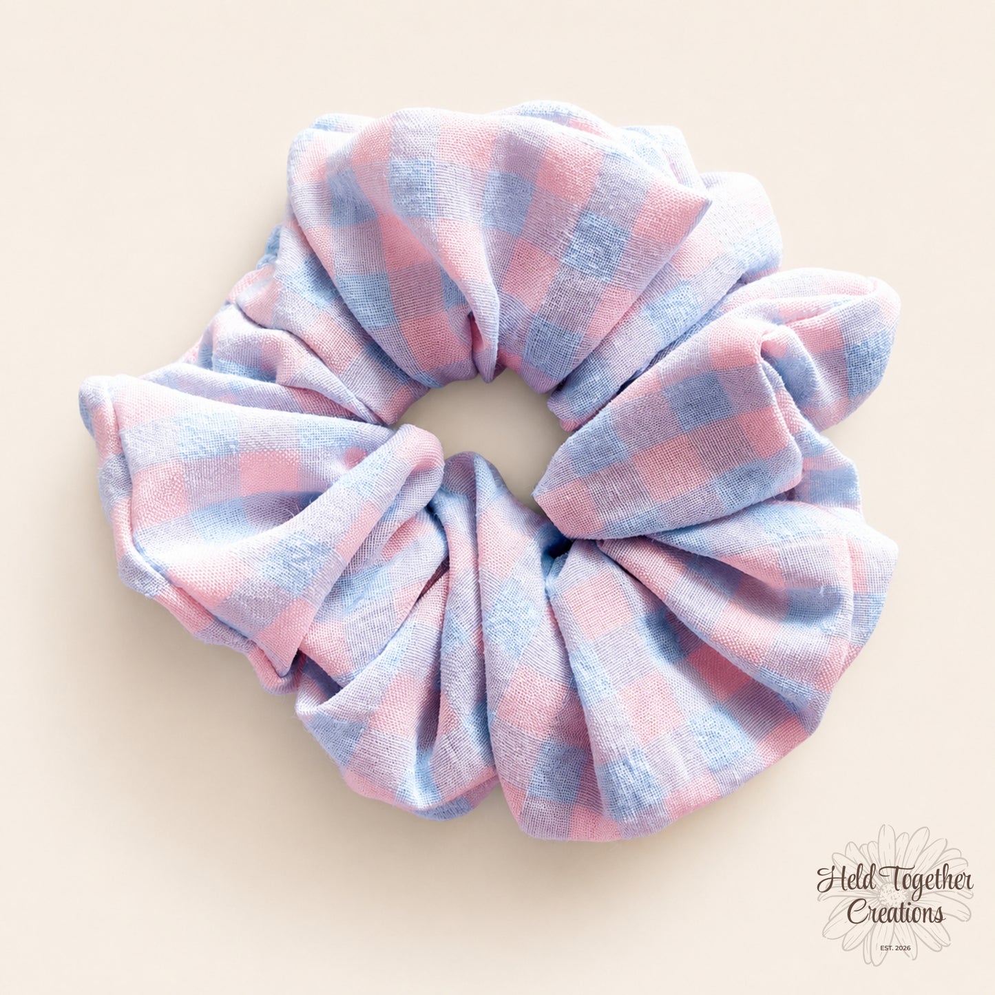 Pastel Picnic handmade fabric scrunchie with a soft pink and blue check pattern on a warm neutral background.
