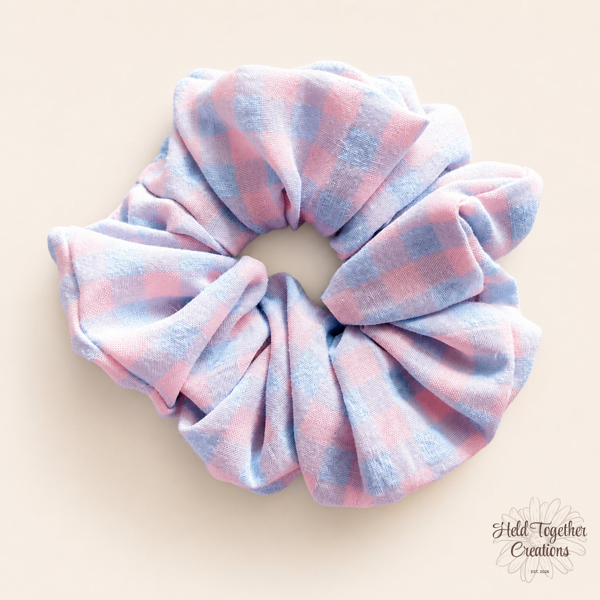 Pastel Picnic handmade fabric scrunchie with a soft pink and blue check pattern on a warm neutral background.