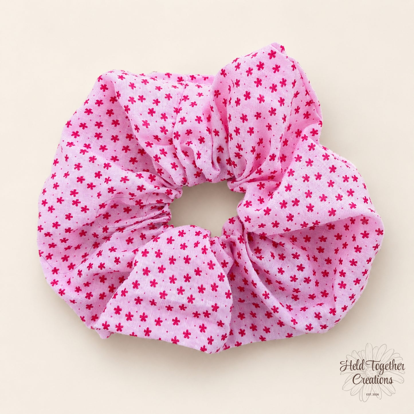 Pink scrunchie with red floral pattern on a beige background