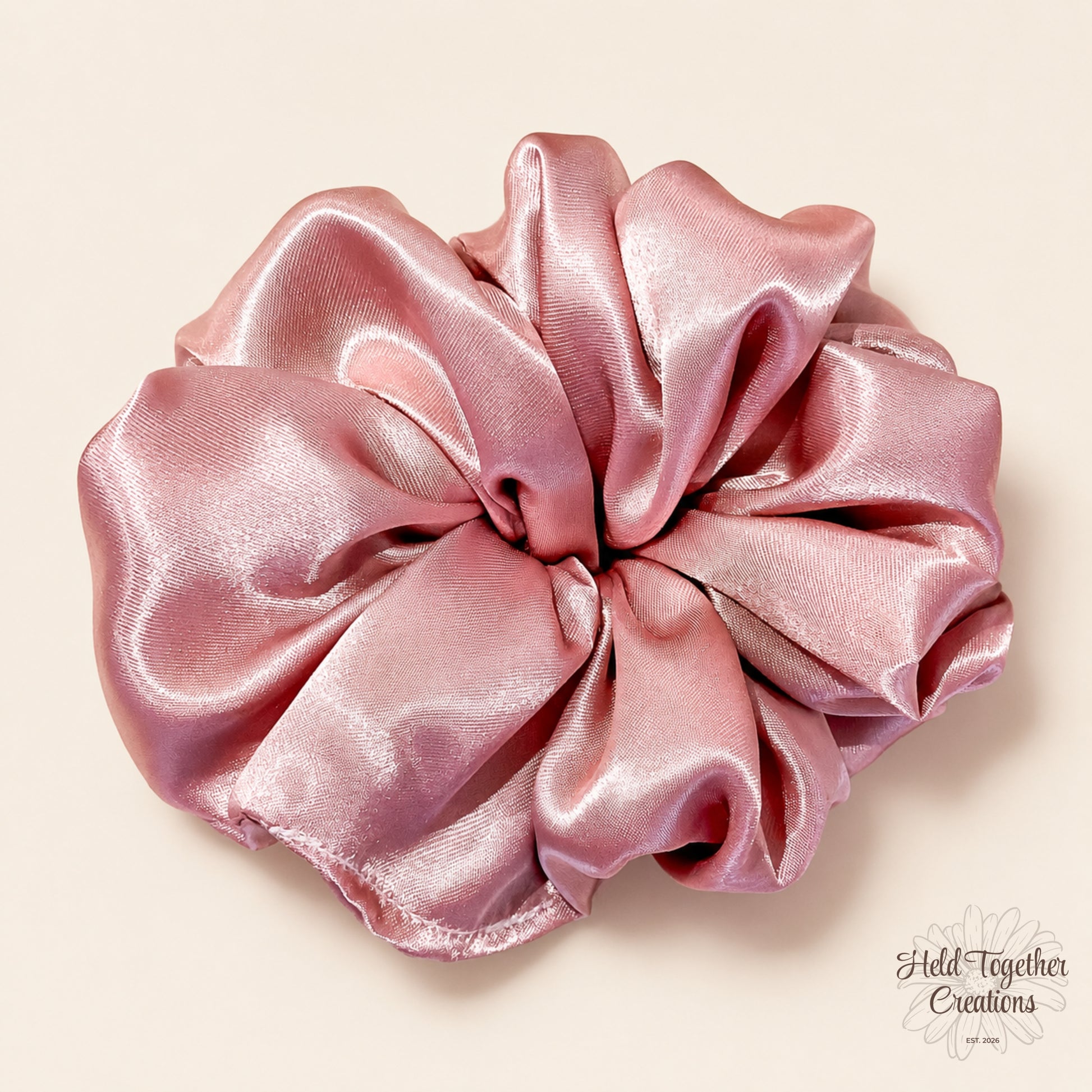 Pink Champagne handmade scrunchie in glossy blush pink satin-style fabric on a soft ivory background.