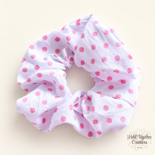 White handmade scrunchie with pink dot print on a soft neutral background.