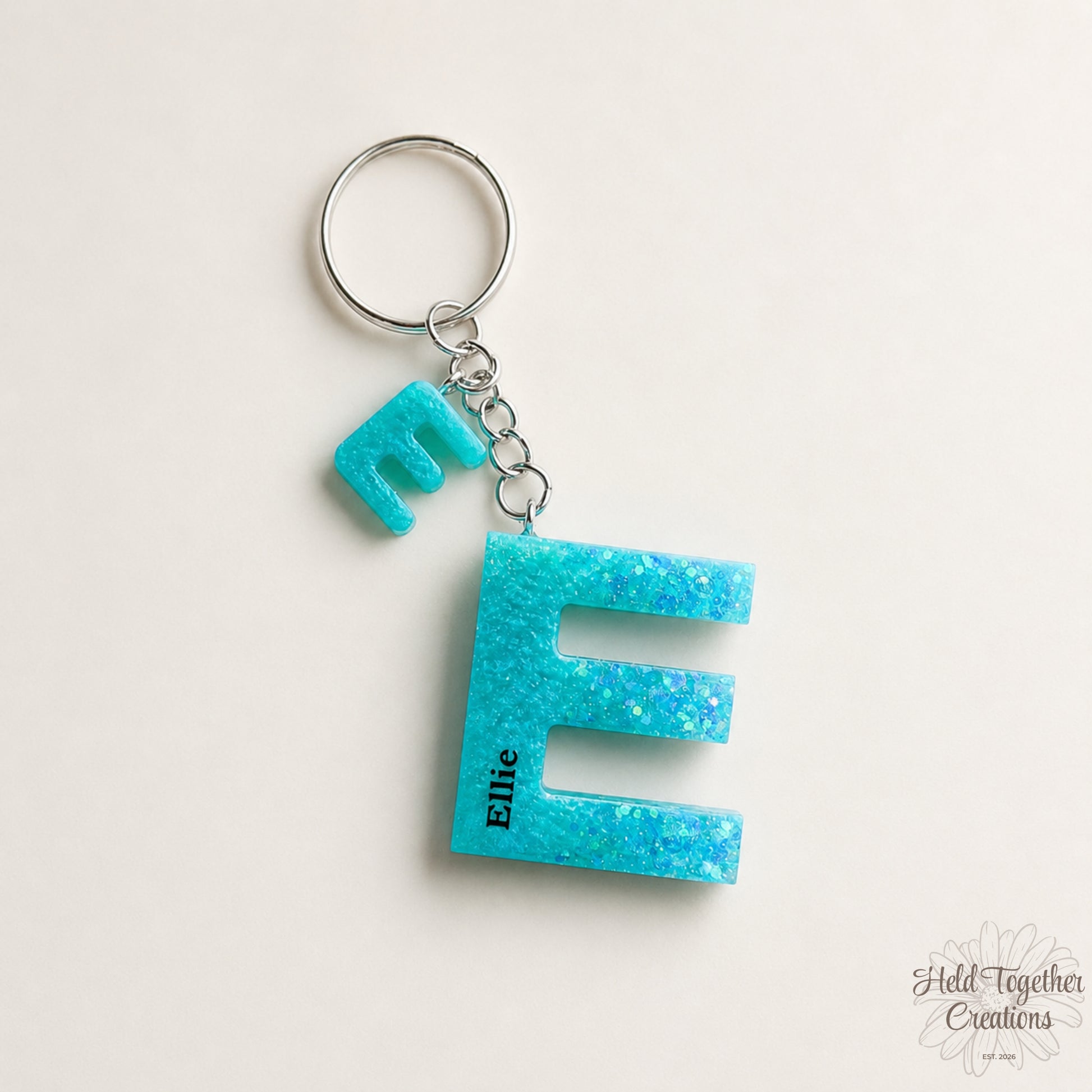 Turquoise glittery letter 'E' keychain on a white background