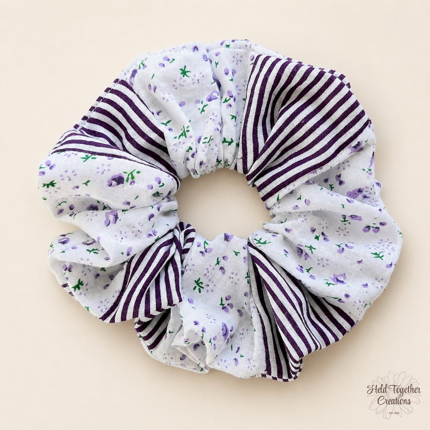 Plum Petal Scrunchie on a warm ivory background with lavender floral print and plum striped fabric panels.