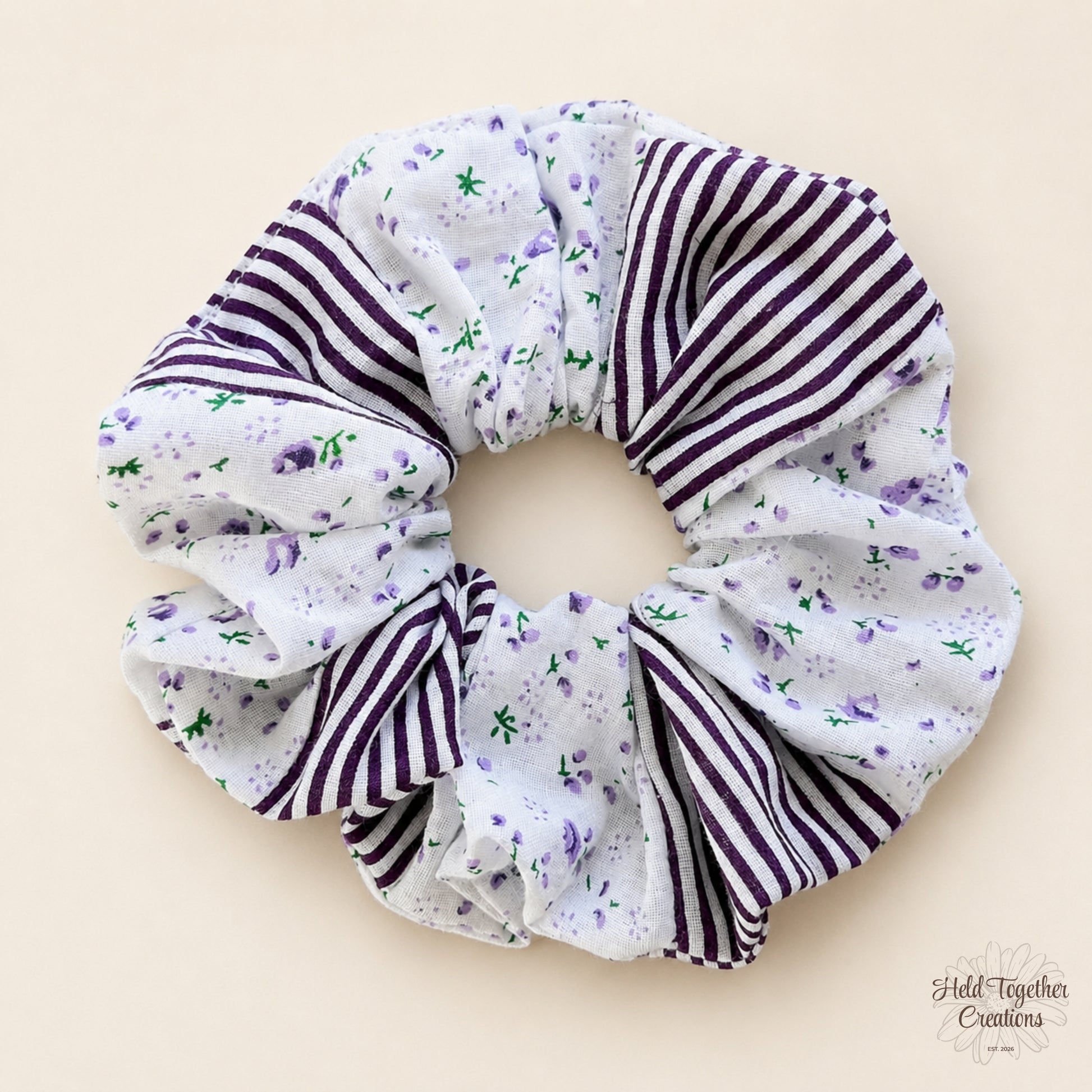 Plum Petal Scrunchie on a warm ivory background with lavender floral print and plum striped fabric panels.