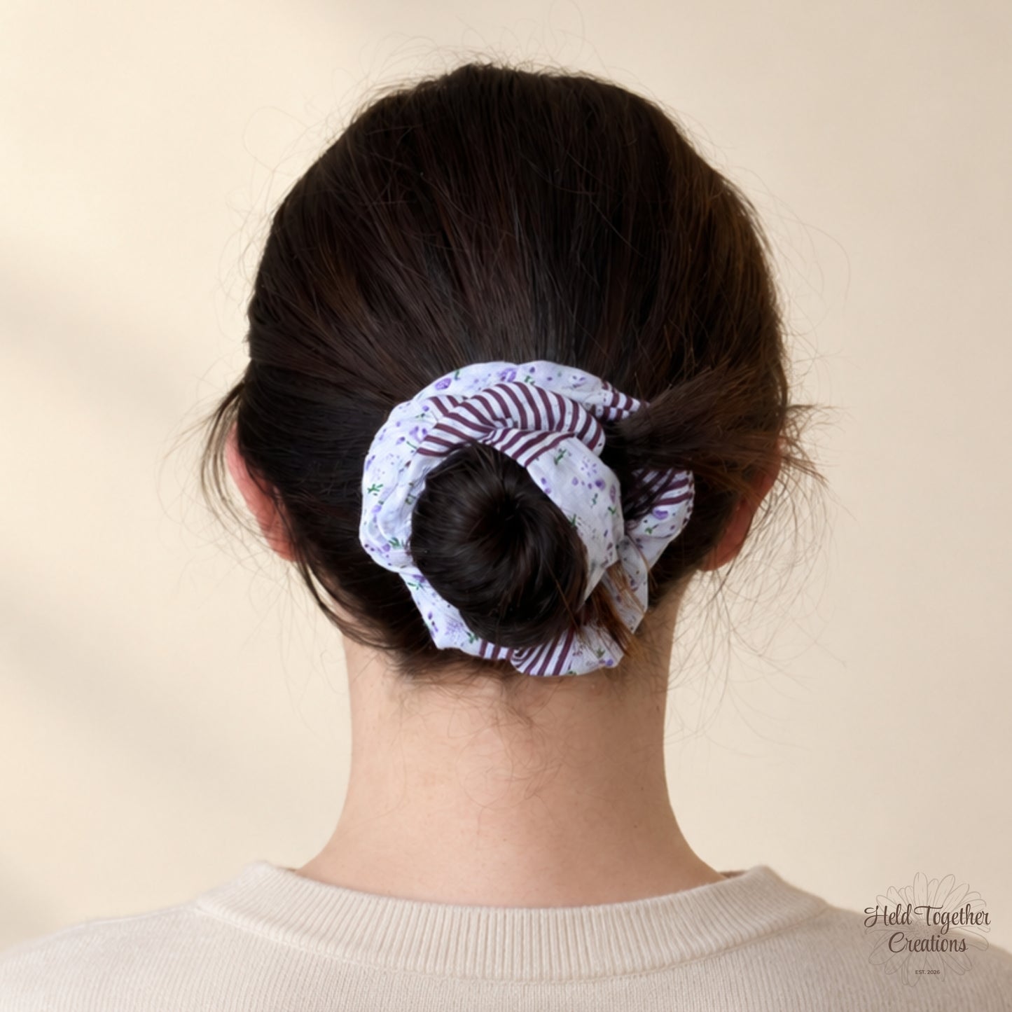 Plum Petal Scrunchie styled in a low bun, showing lavender floral fabric and plum stripe panels.