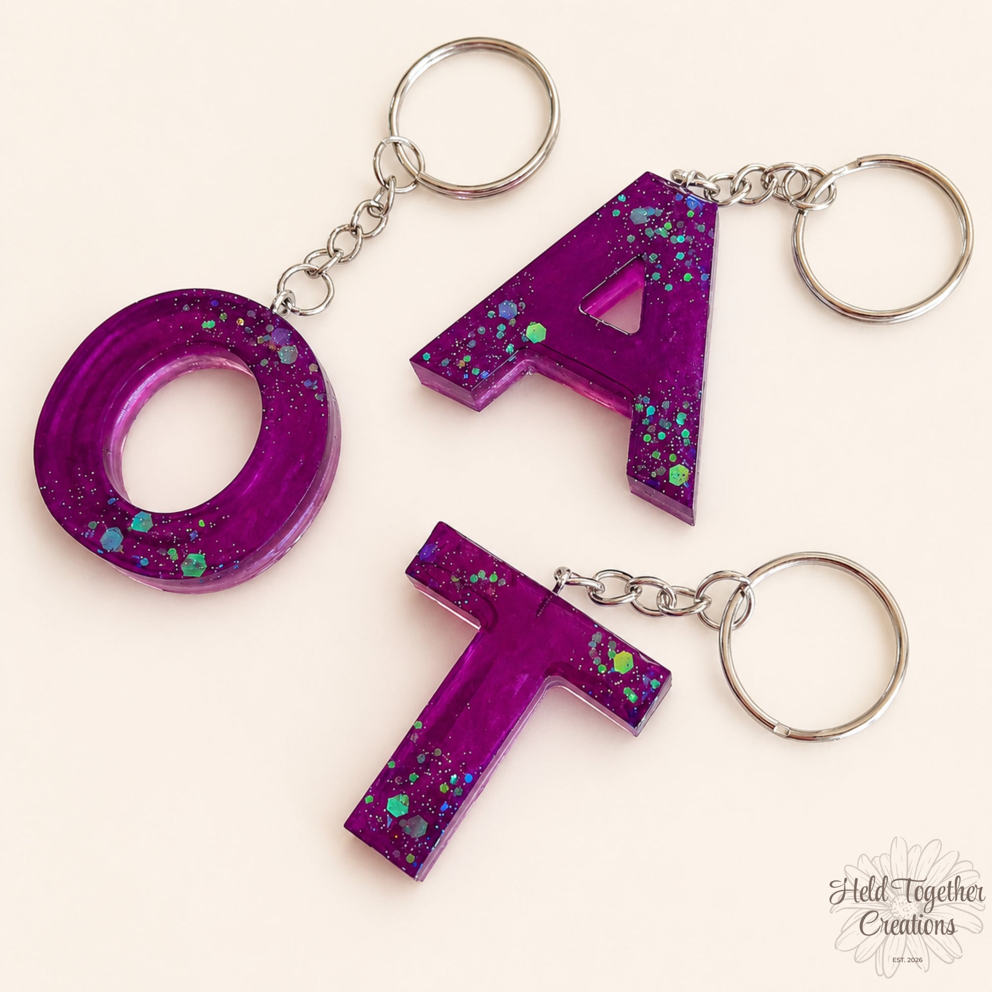 Purple handmade resin initial keyrings with glitter details and silver keyring hardware.