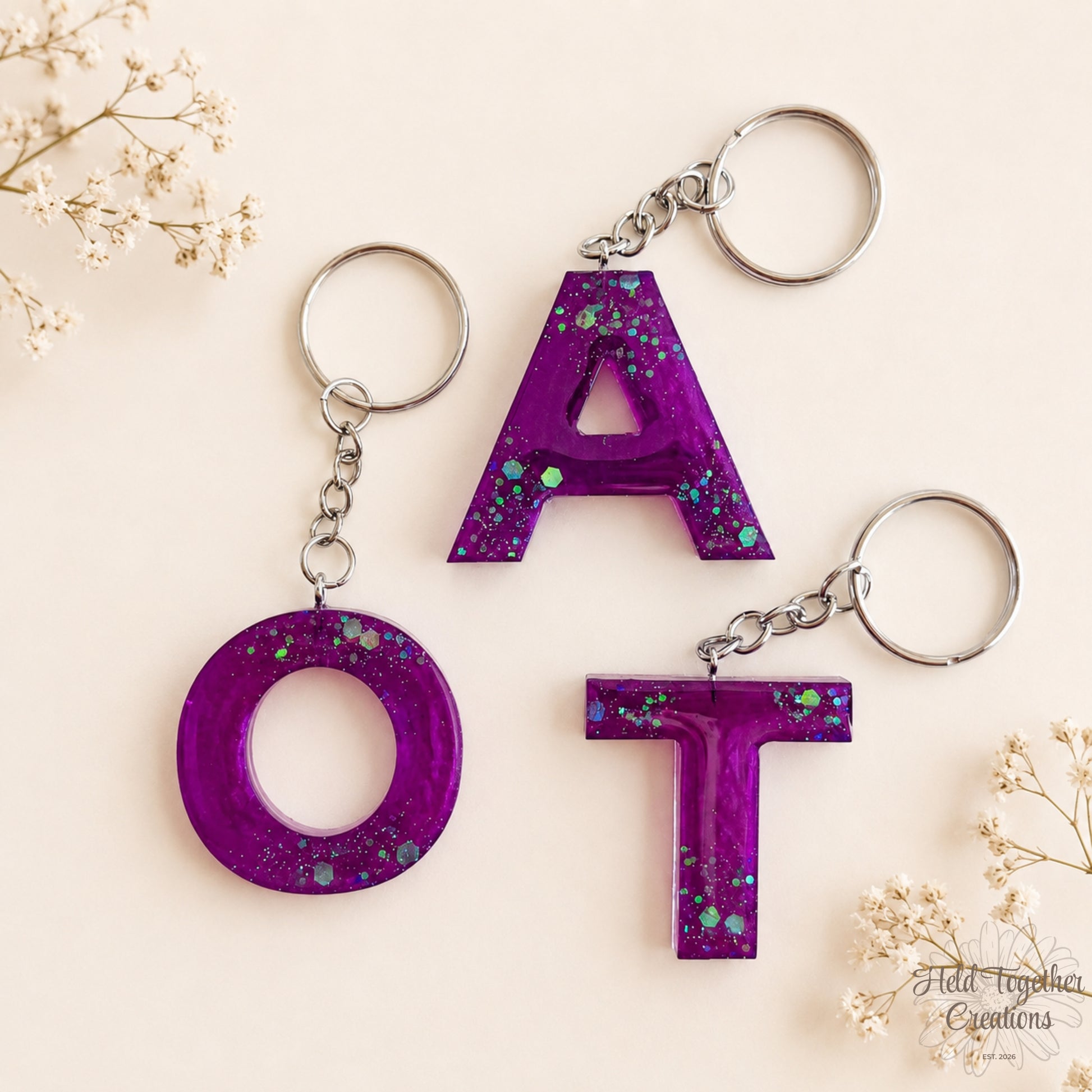 Purple handmade resin initial keyrings with glitter details and silver keyring hardware.
