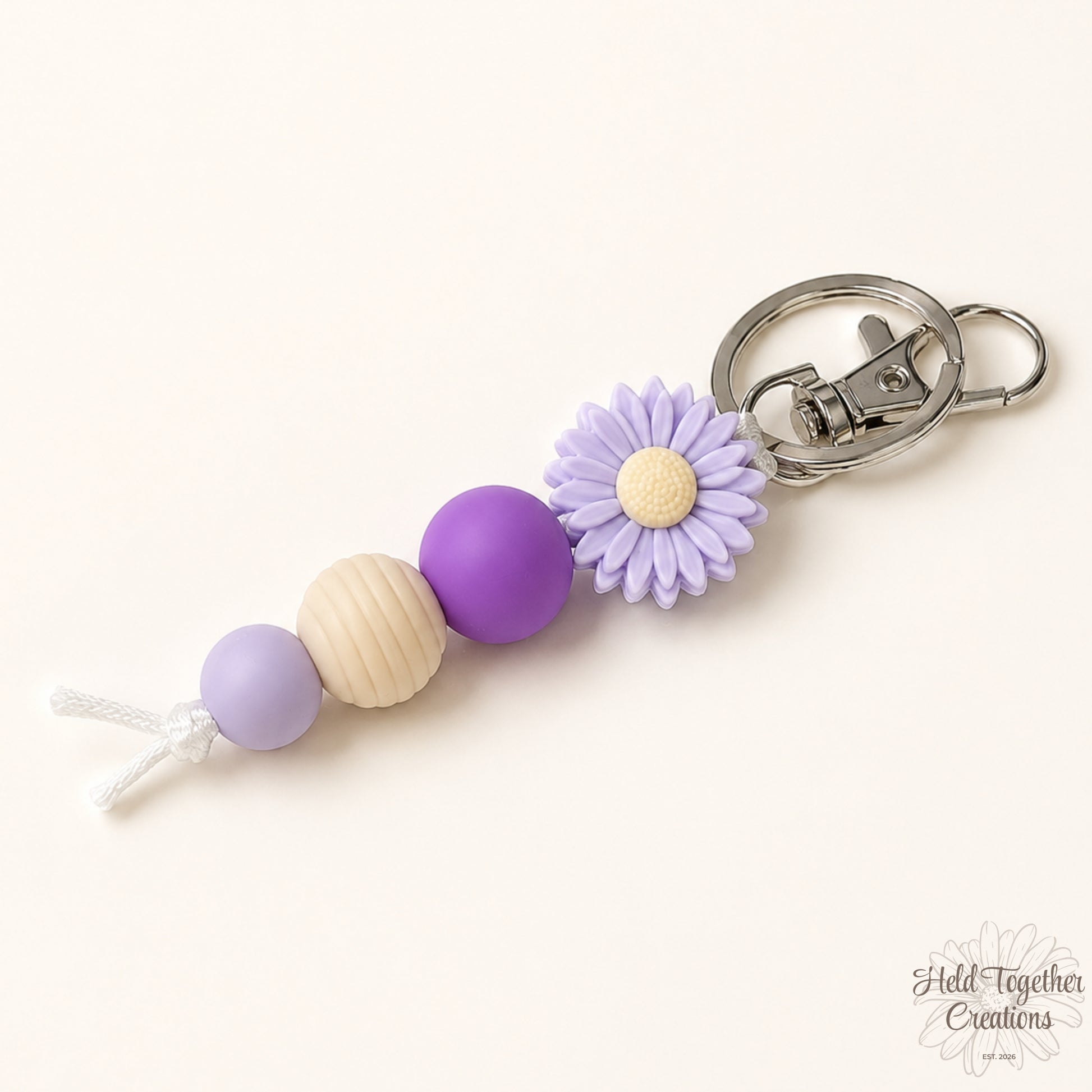 Keychain with purple beads and a flower charm on a white background