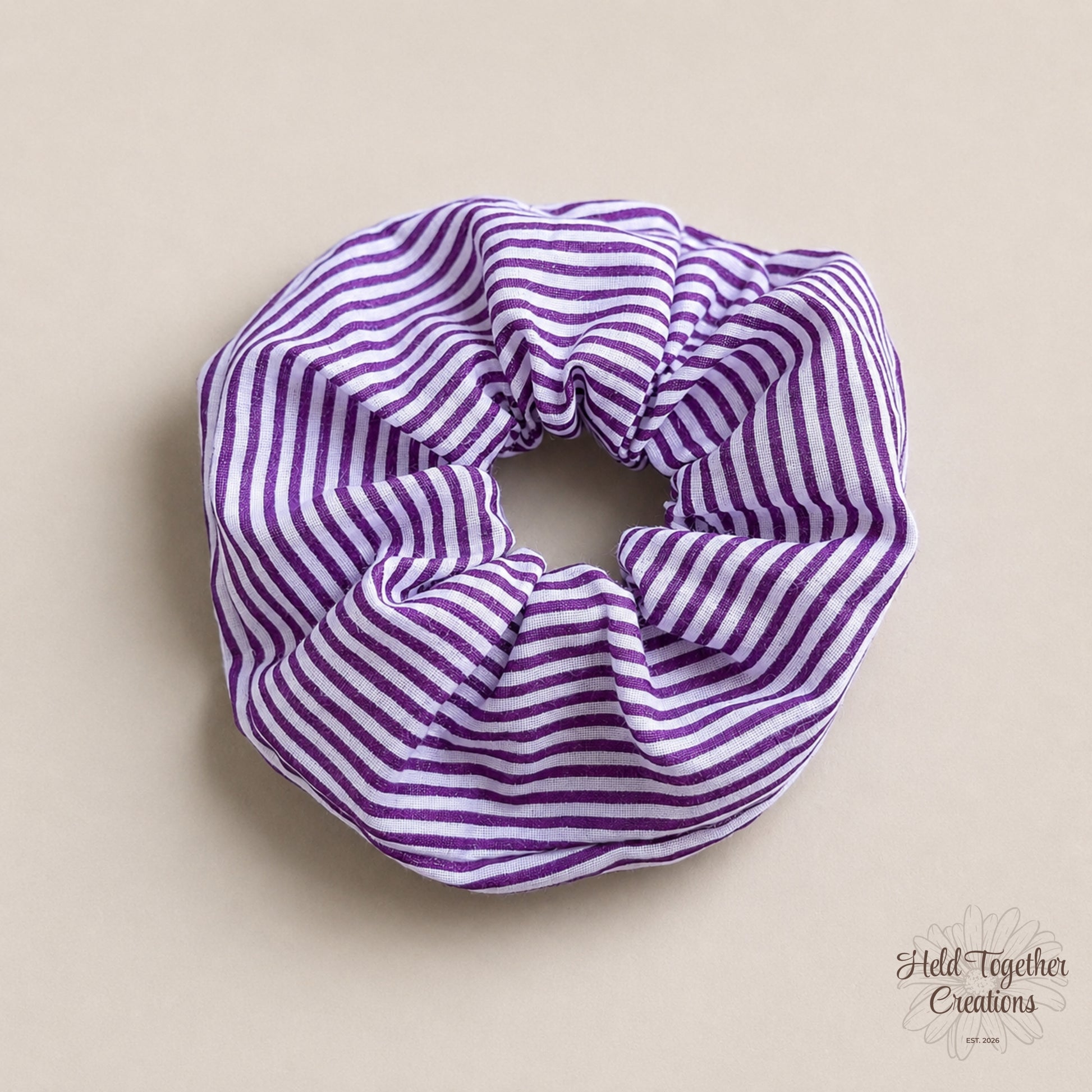 Purple and white striped scrunchie on a beige background