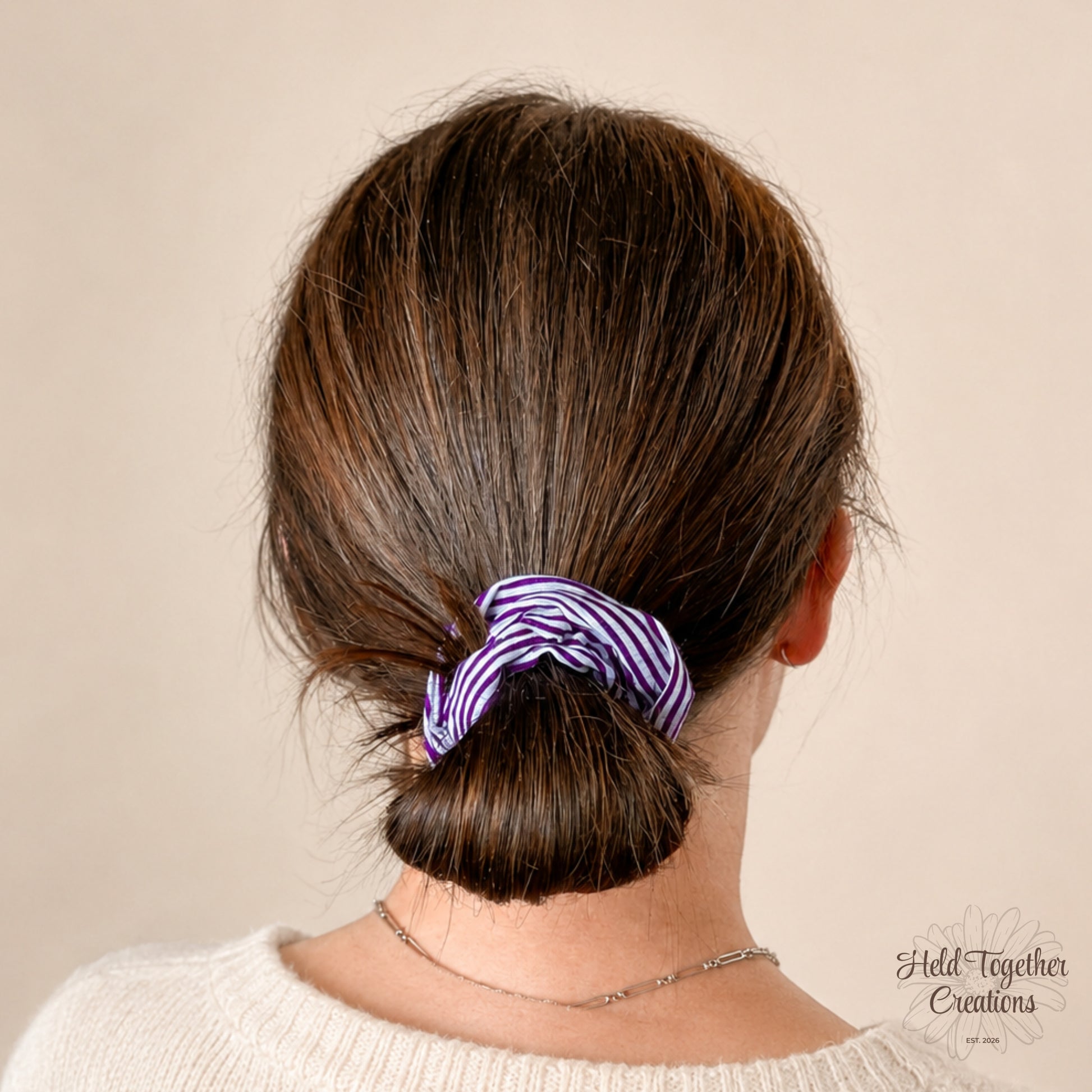 Purple and white striped scrunchie on a beige background