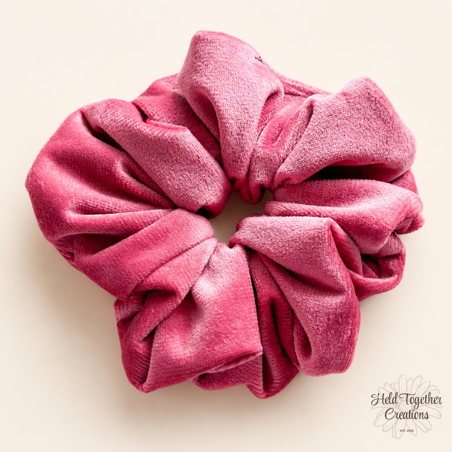 Pink velvet handmade scrunchie on a warm ivory background.