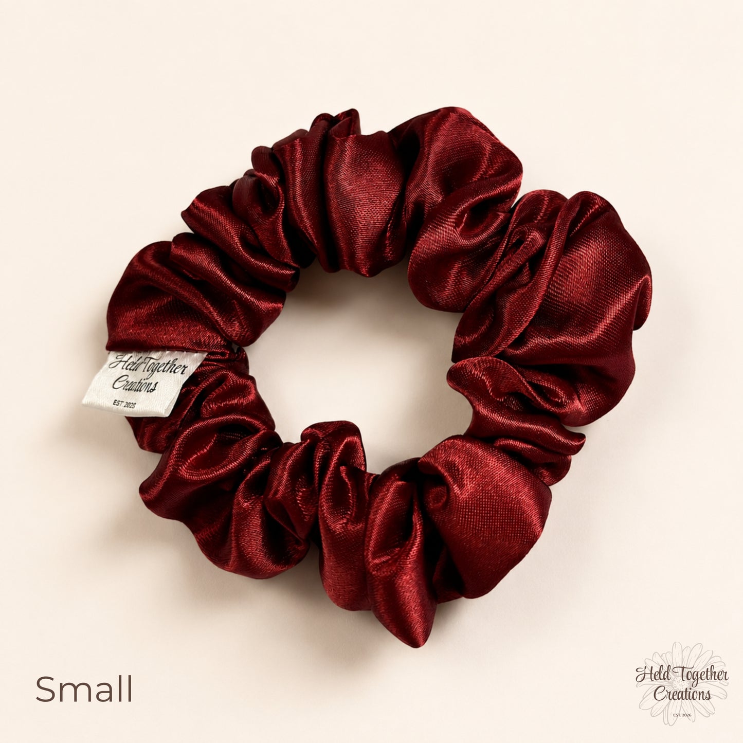 Small ruby satin scrunchie on a warm ivory background