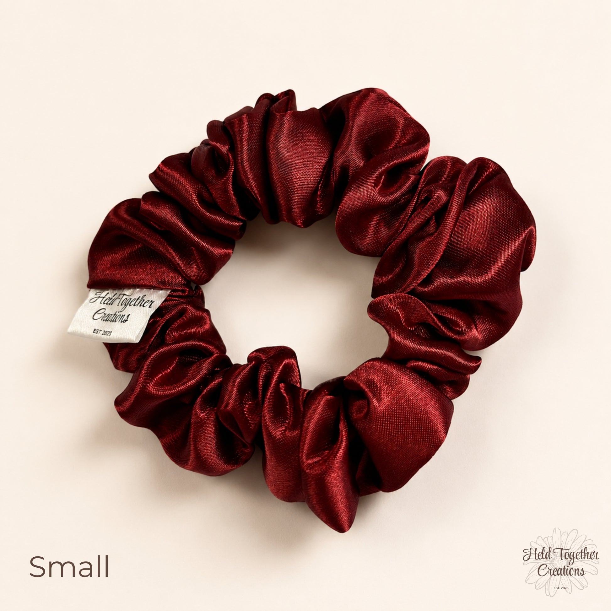 Small ruby satin scrunchie on a warm ivory background