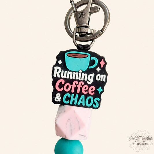 Handmade Running on Coffee and Chaos silicone bead keyring with teal, pink and marble-style beads on a warm ivory background.