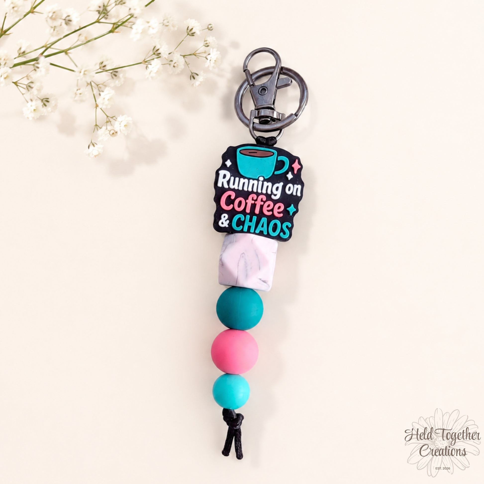 Handmade Running on Coffee and Chaos silicone bead keyring with teal, pink and marble-style beads on a warm ivory background.