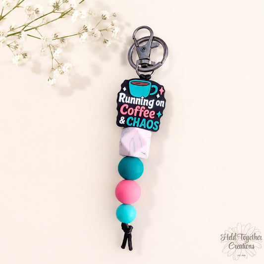 Handmade Running on Coffee and Chaos silicone bead keyring with teal, pink and marble-style beads on a warm ivory background.