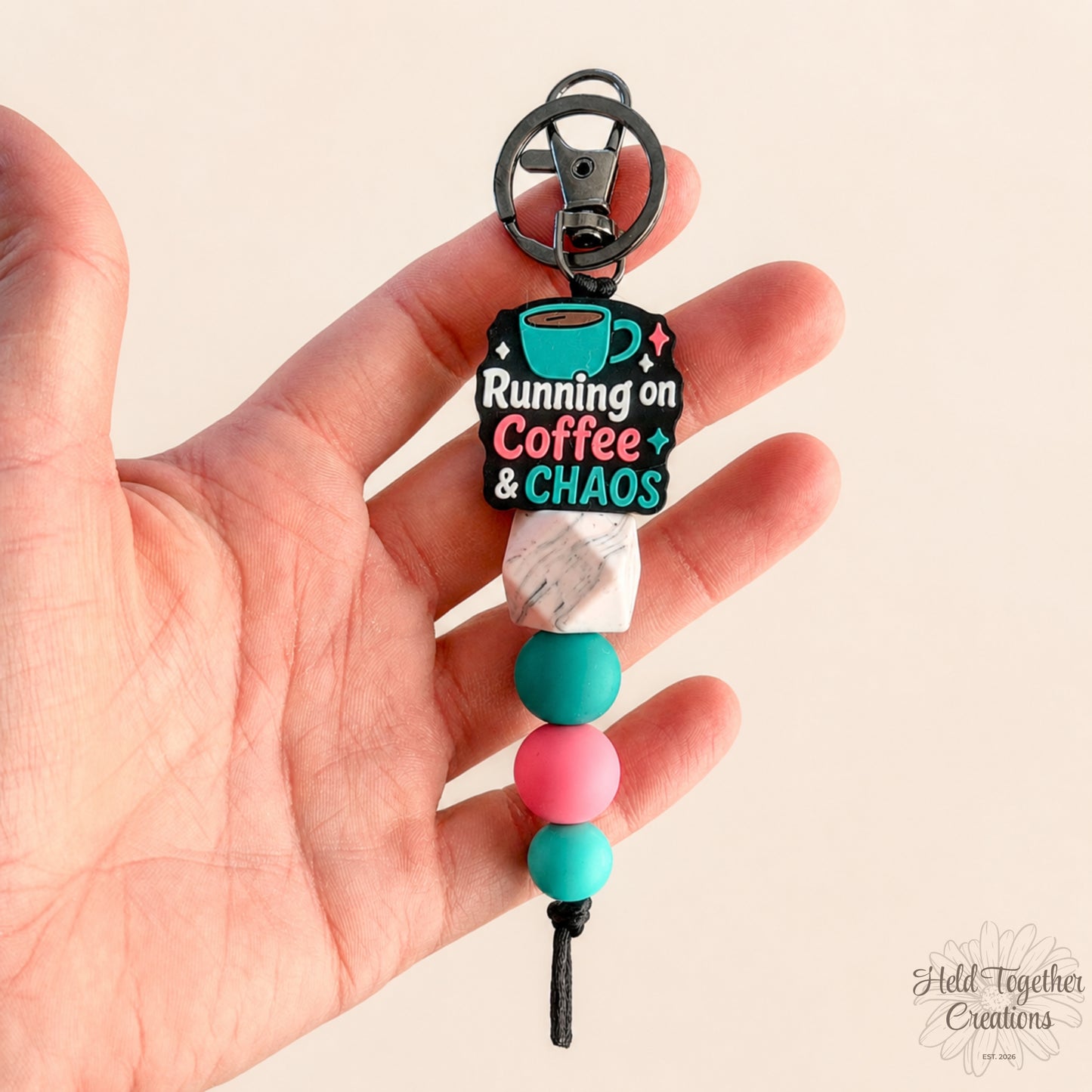 Handmade Running on Coffee and Chaos silicone bead keyring with teal, pink and marble-style beads on a warm ivory background.