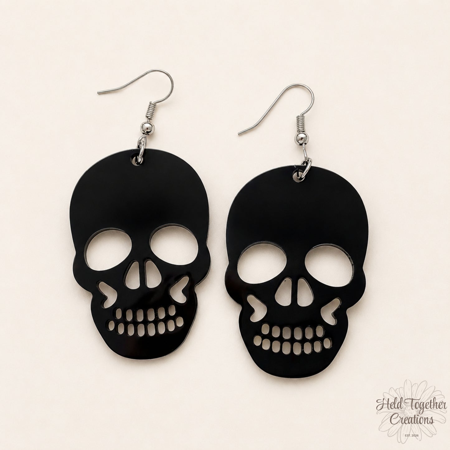 Black skull-shaped earrings on a beige background