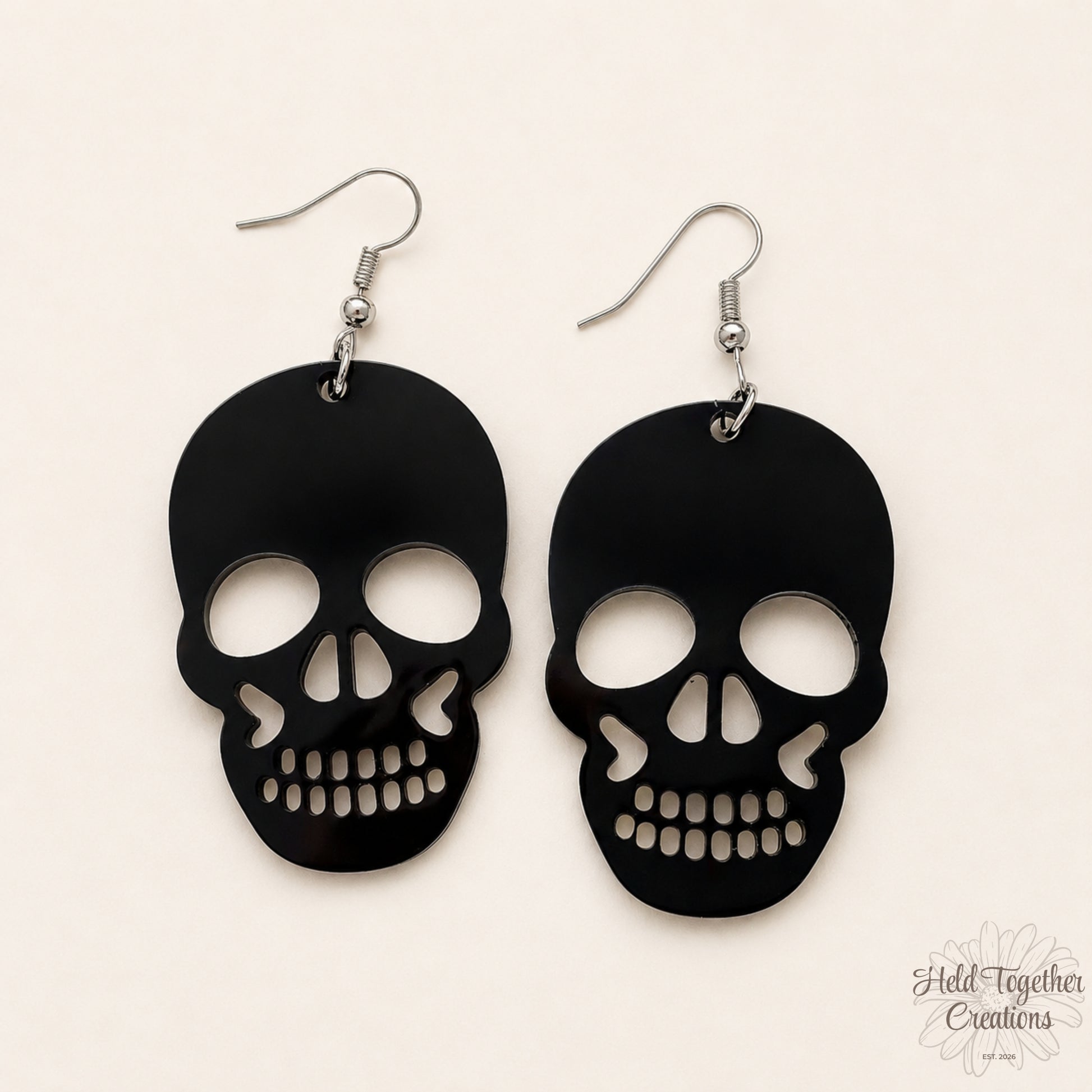 Black skull-shaped earrings on a beige background
