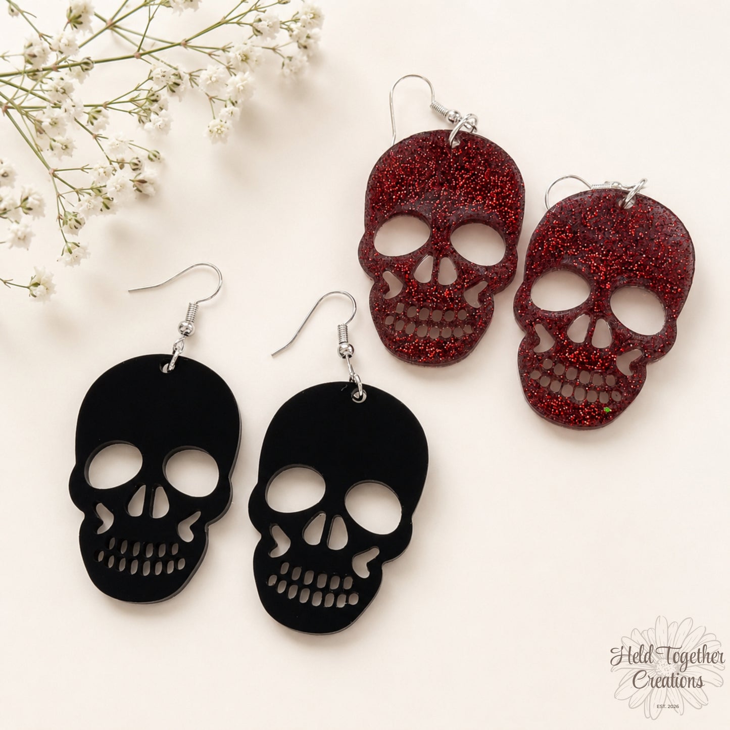 Black and red skull-shaped earrings on a white background with small white flowers.