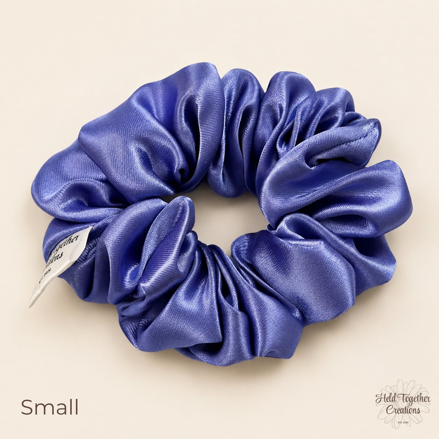 Small lilac satin scrunchie laid flat showing shiny gathered satin fabric.