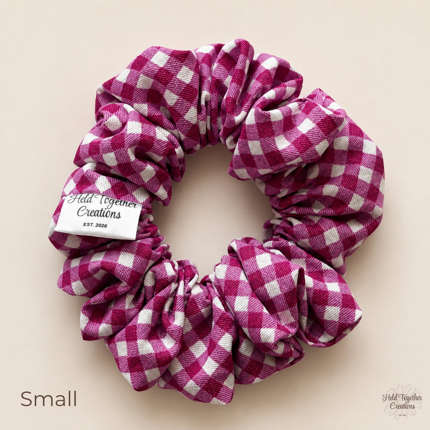 Small mulberry pink and white gingham cotton scrunchie shown from above.