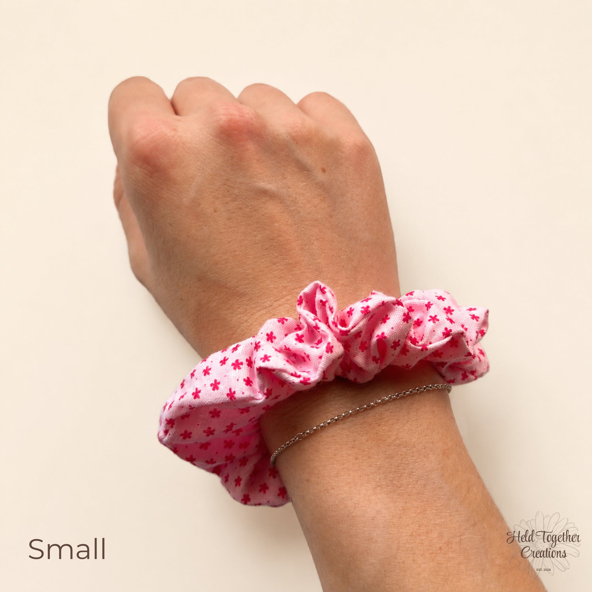 Small Petal Sprinkle Scrunchie shown on wrist with pink floral fabric and gathered shape.